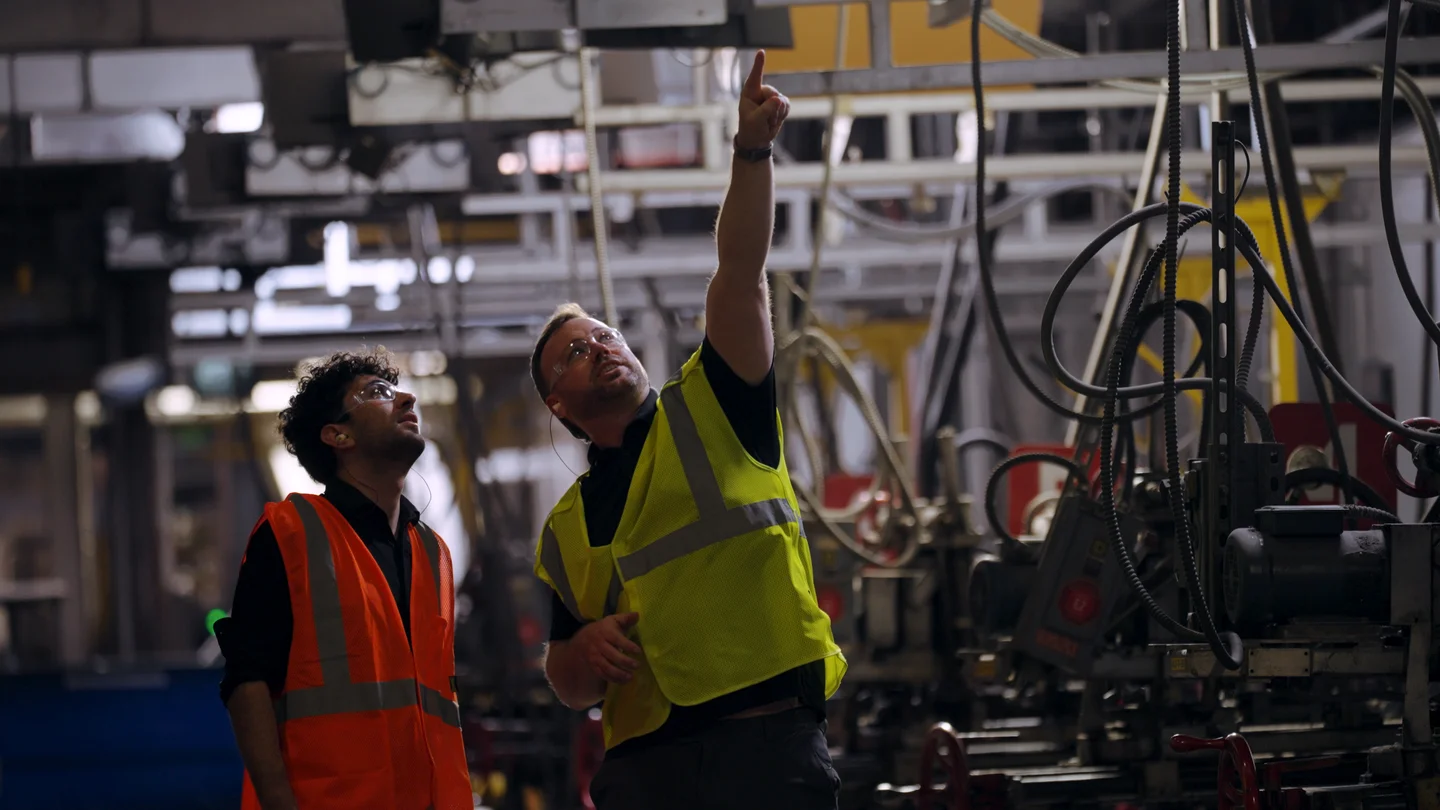 A Carlex team member explaining production equipment during a factory visit